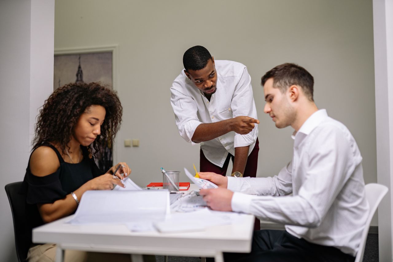 Manager instructing employees during a focused team meeting in a modern office setting.