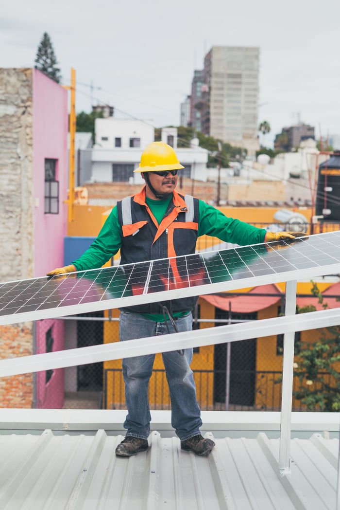 A solar technician adjusts photovoltaic panels on a colorful urban rooftop.